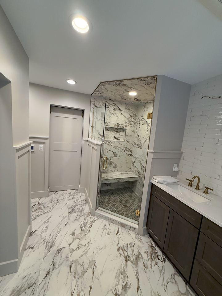 Finished bathroom with marble-look tile shower and floor